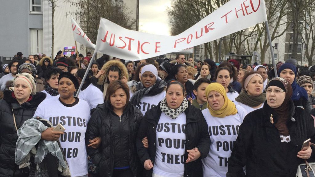 People march in the streets of Aulnay-sous-Bois, north of Paris, France, holding a sign reading