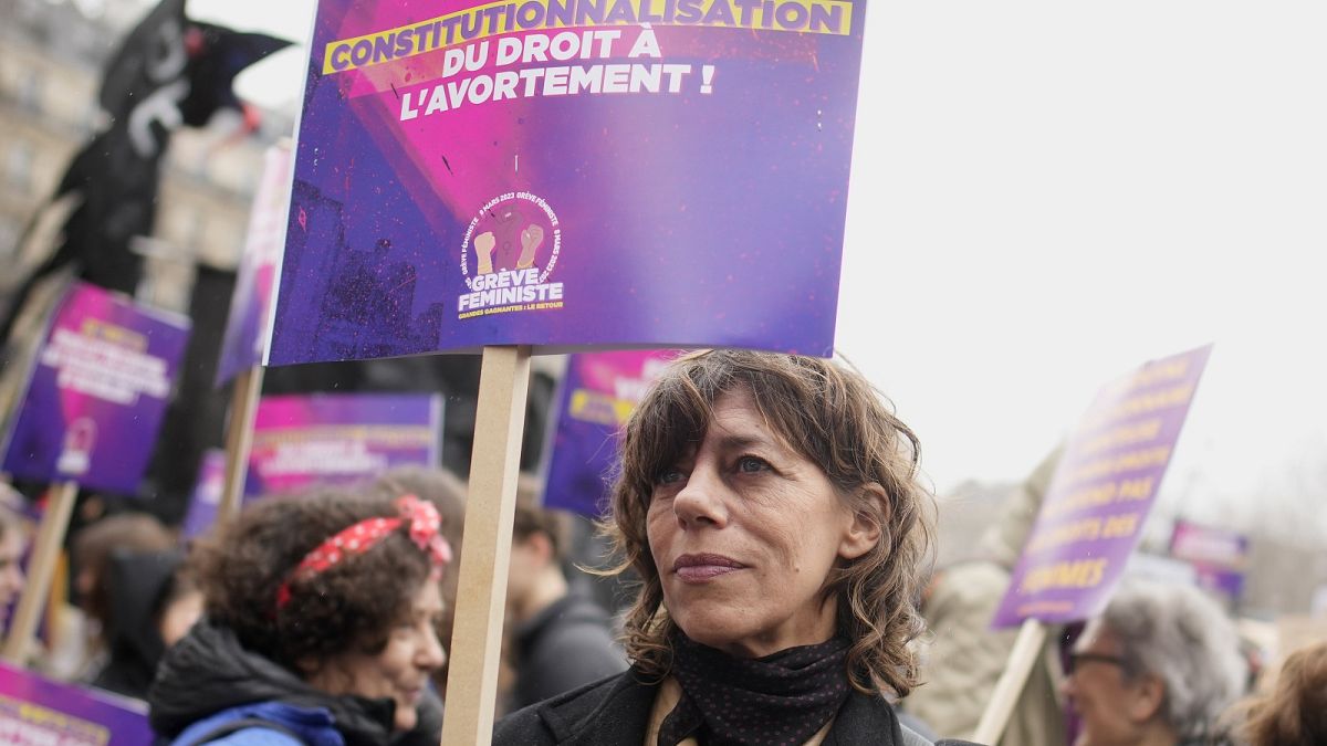 A woman demonstrates with a poster reading "Abortion in the Constitution" as part of the International Women