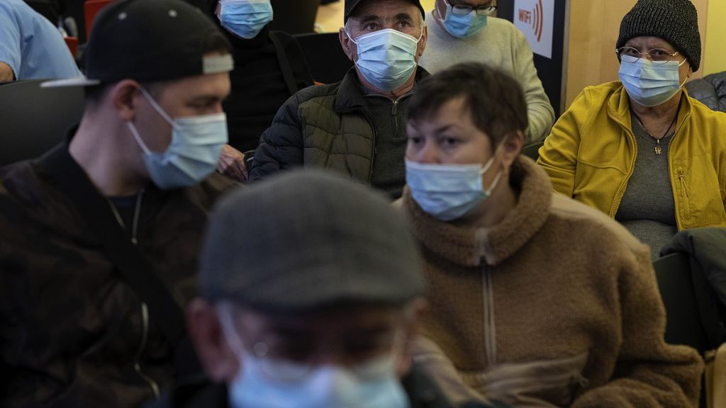 People wearing face masks as a precaution wait for a doctor appointment inside a hospital in Barcelona.