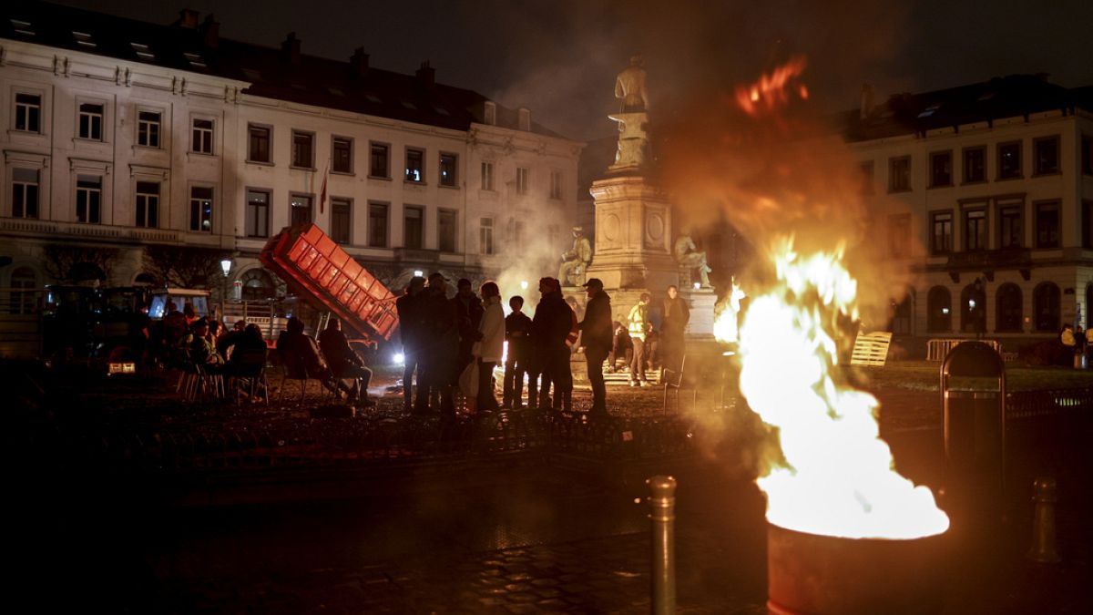 Farmers get warm around a fire as they gather for a protest outside the European Parliament ahead of an EU summit in Brussels.