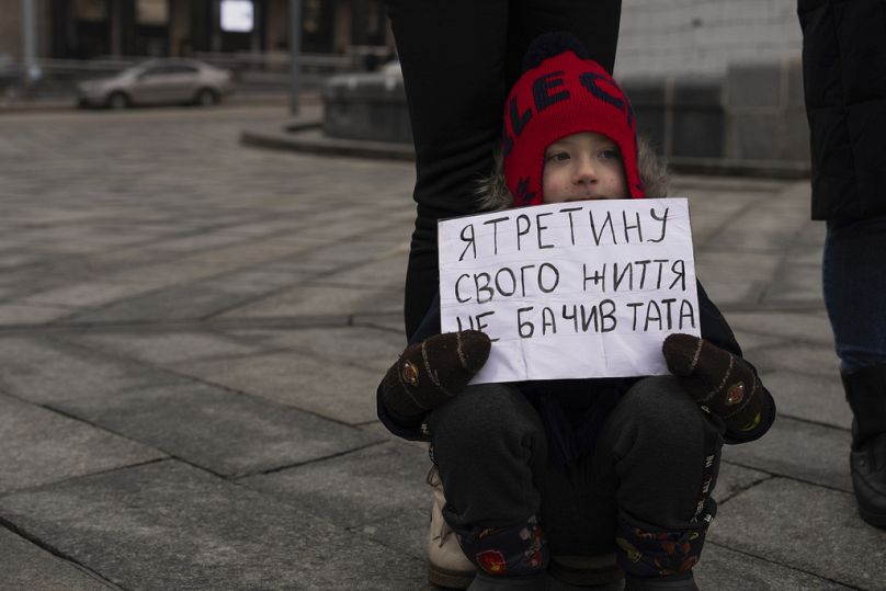 Matvii, lat 4, czyta plakat "Nie widziałem ojca przez trzecią część mojego życia"podczas wiecu na placu Niepodległości w Kijowie, styczeń 2024 r