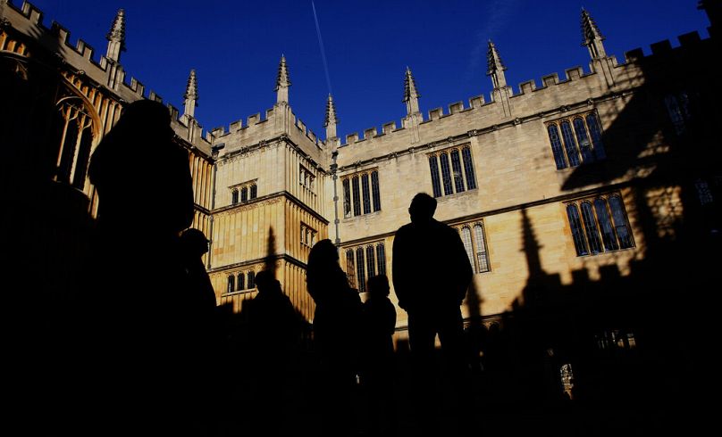 Sylwetki ludzi w Old Schools Quadrangle, Old Bodleian Library po raz pierwszy otwarto dla uczonych w 1602 roku na Uniwersytecie Oksfordzkim w Oksfordzie, październik 2008