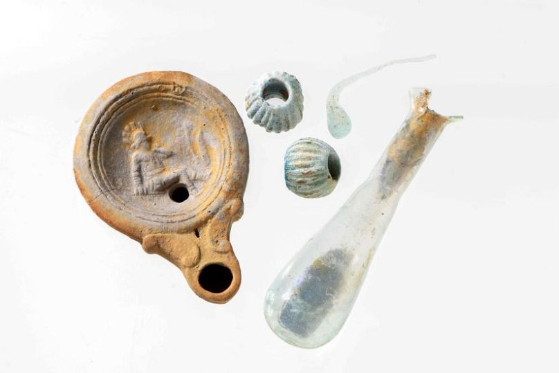 Lampa rzymska, szklana fiolka i koraliki z miejsca odkrycia.