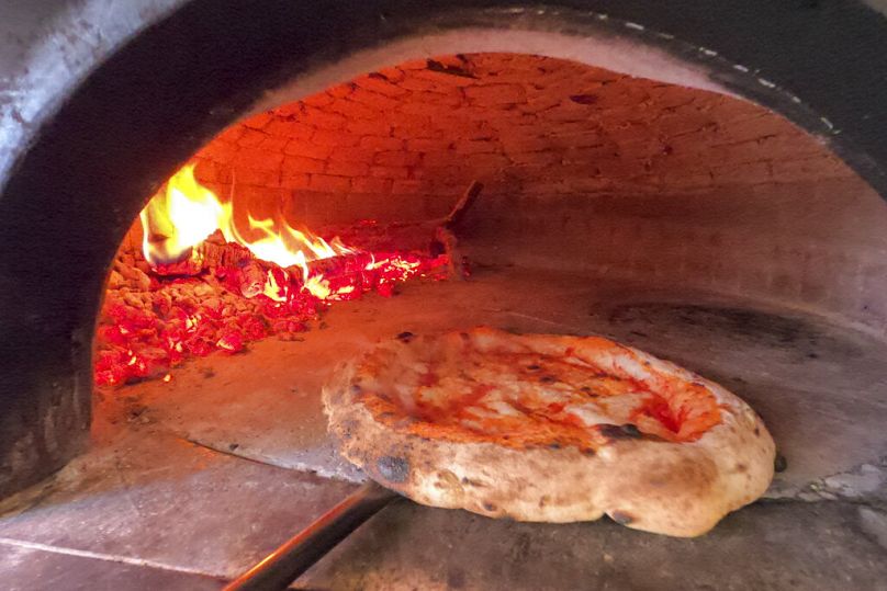 Samodzielna pizza?  Dlaczego nie!  Pizza jest pieczona w piecu opalanym drewnem w pizzerii Caputo w Neapolu we Włoszech