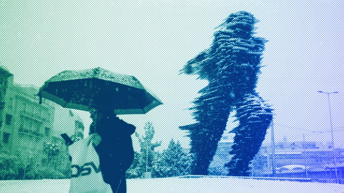 A woman with an umbrella walks past the Runner, a sculptured by Kostas Varotsos, during a snowstorm, in Athens, February 2023