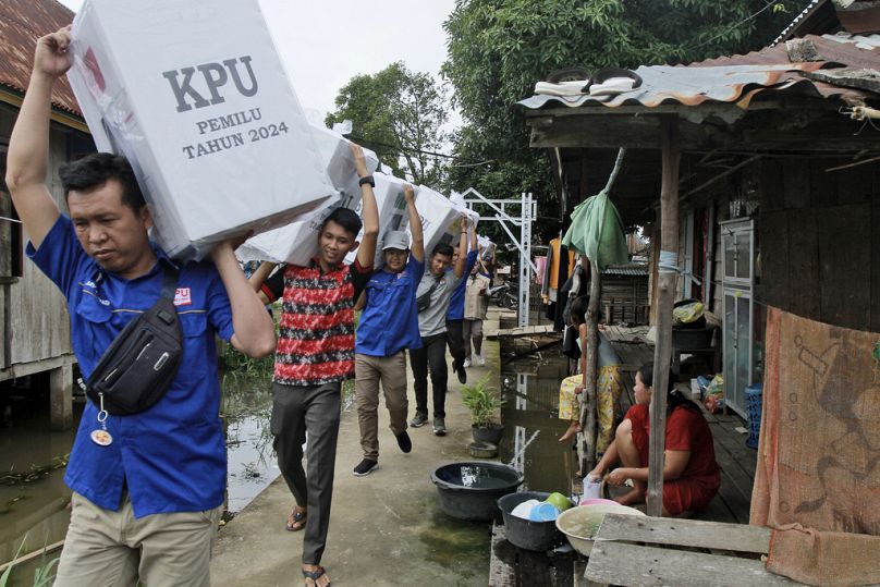 Pracownicy wyborczy niosą urny wyborcze podczas rozdawania akcesoriów wyborczych w odległych wioskach, Pemulutan na Sumatrze Południowej, luty 2024 r.