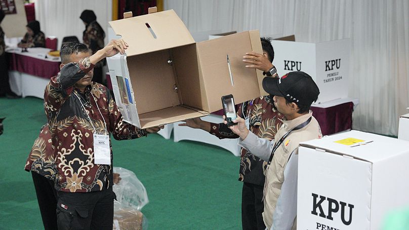 Pracownicy wyborczy pokazują pustą urnę wyborczą podczas otwierania lokalu wyborczego w Bojong Koneng