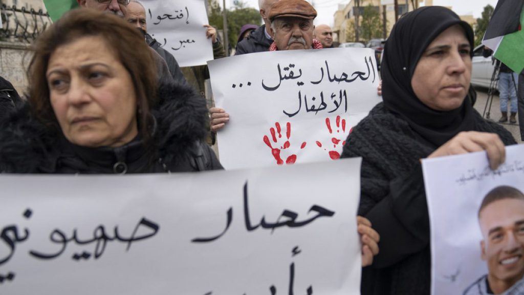 Palestinian activists carry posters, one reads