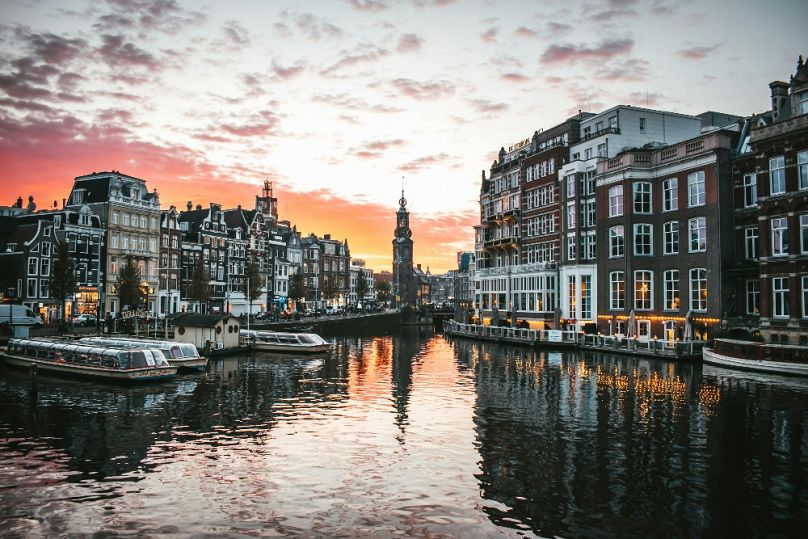 Zachód słońca nad Muntplein w Amsterdamie, odbity w pięknych kanałach miasta