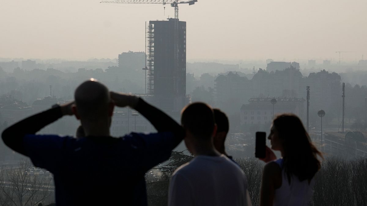 Athletes take a break as they run at the San Siro hill and look at the view skyline of Milan, Italy, Tuesday, Feb. 20, 2024.