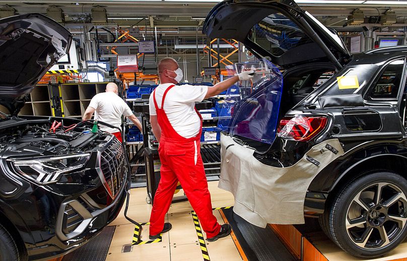 Pracownicy noszący maski ochronne wznawiają produkcję samochodów w fabryce Audi w Gyor na Węgrzech, kwiecień 2020 r