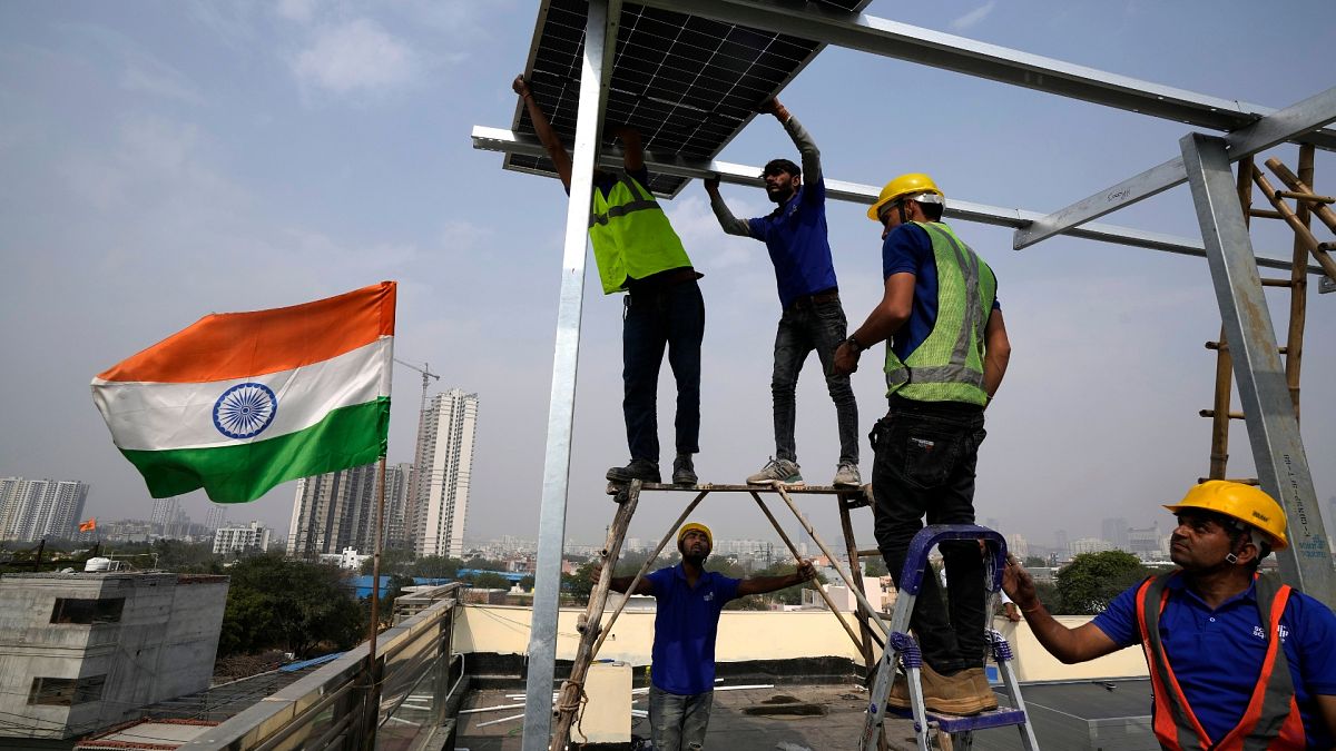 Workers of Solar Square place a panel on the rooftop of a residence in Gurugram on the outskirts of New Delhi.