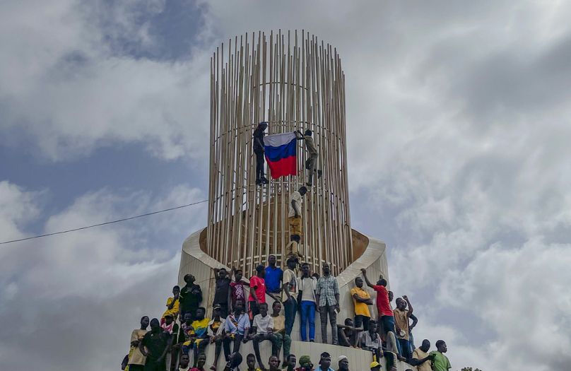 Zwolennicy junty rządzącej Nigrem trzymają rosyjską flagę na początku protestu w Niamey, sierpień 2023 r.