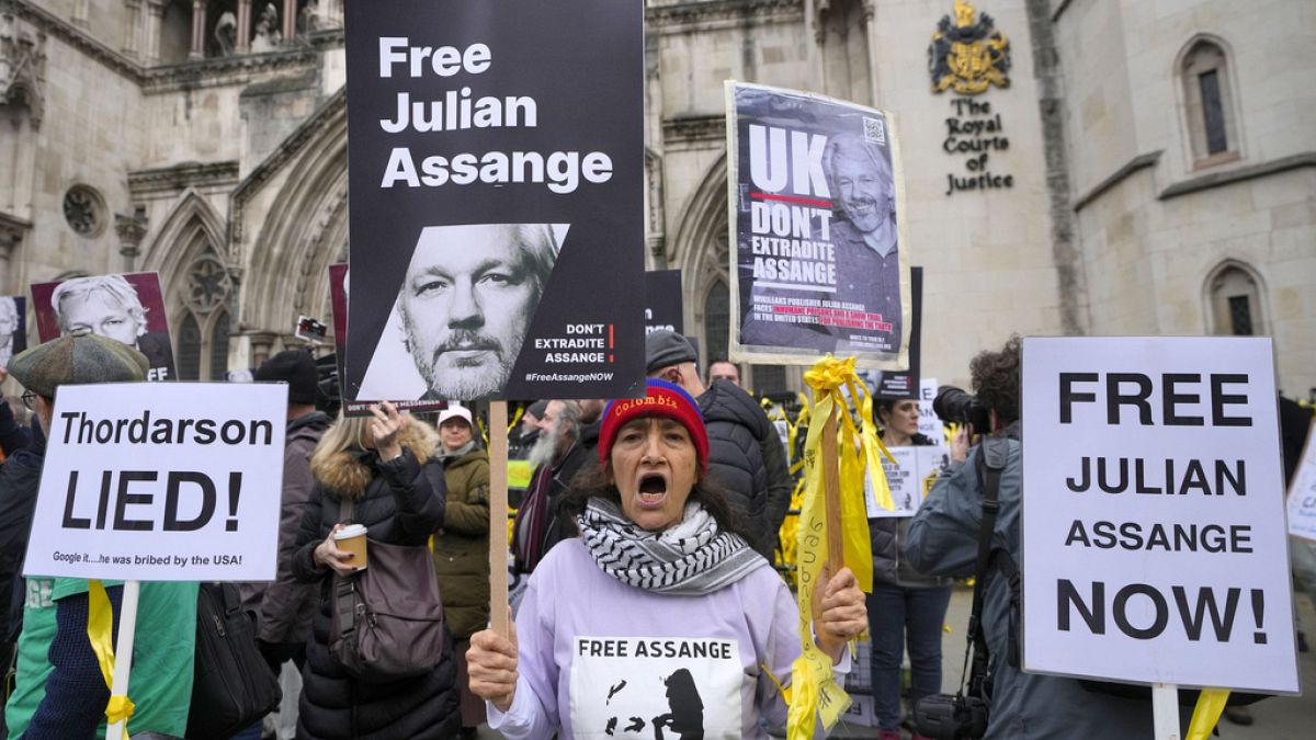 Demonstrators hold banners outside the Royal Courts of Justice in London, Tuesday, 20 February, 2024.