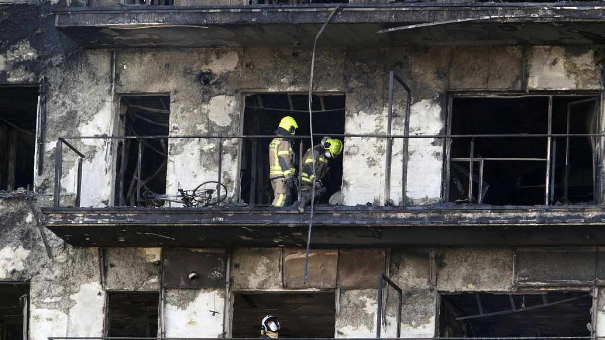 Firefighters remove a charred body inside a burned block building in Valencia, Spain, Friday, Feb. 23, 2024.