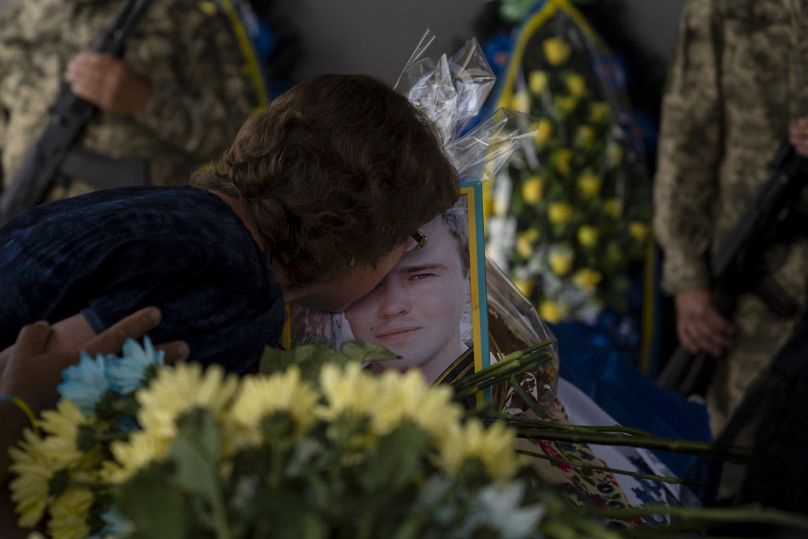 Żynaida Niedoleszko całuje zdjęcie swojego siostrzeńca Romana Szadłowskiego podczas nabożeństwa pogrzebowego w jego intencji w Buczy, lipiec 2023 r.