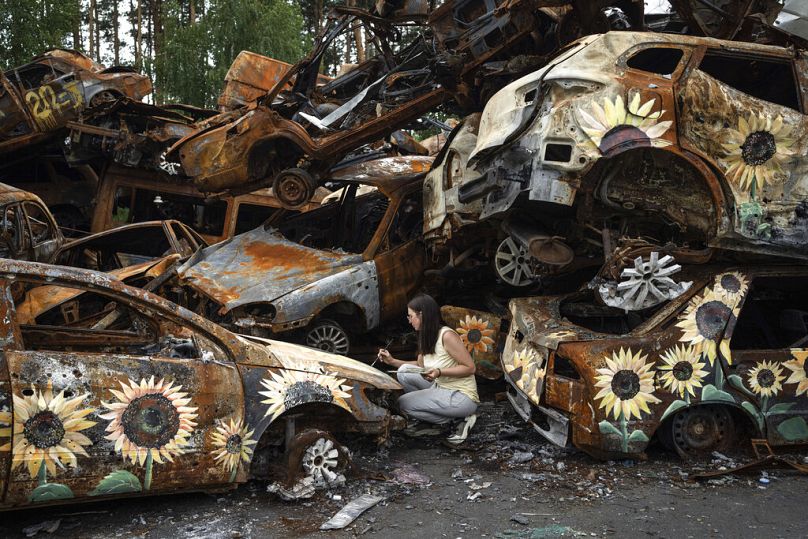 Ukraińska artystka Olena Yanko maluje słoneczniki na samochodach zniszczonych w wyniku rosyjskich ataków w Irpinie, sierpień 2022