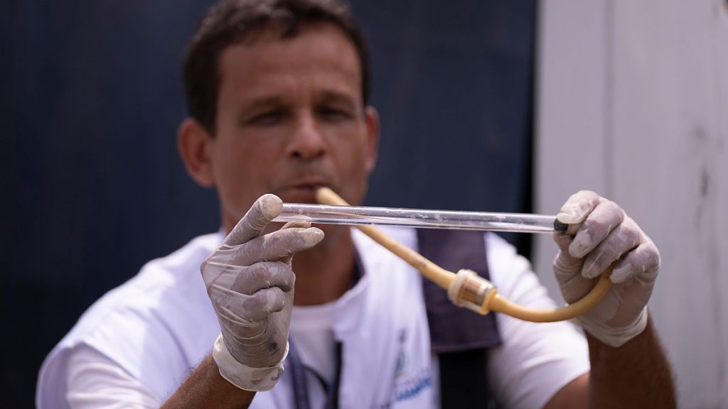 A public health agent holds a tube with a captured mosquito to be taken to a lab for analysis, at a scrapyard in Nova Iguacu, Rio de Janeiro, Brazil, Tuesday, Feb. 6, 2024