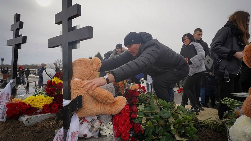 Ludzie złożyli zabawki i kwiaty na grobach rodziny, która zginęła w pożarze, gdy rosyjski dron uderzył w ich dom w dzielnicy mieszkalnej w Charkowie na Ukrainie, 12 lutego 2024 r.