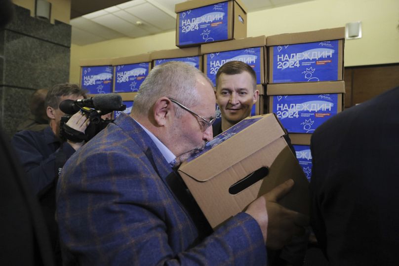 Borys Nadieżdin całuje pudełko z arkuszami subskrypcji z podpisami zebranymi dla niego na zbliżające się wybory prezydenckie w Moskwie, luty 2024 r.