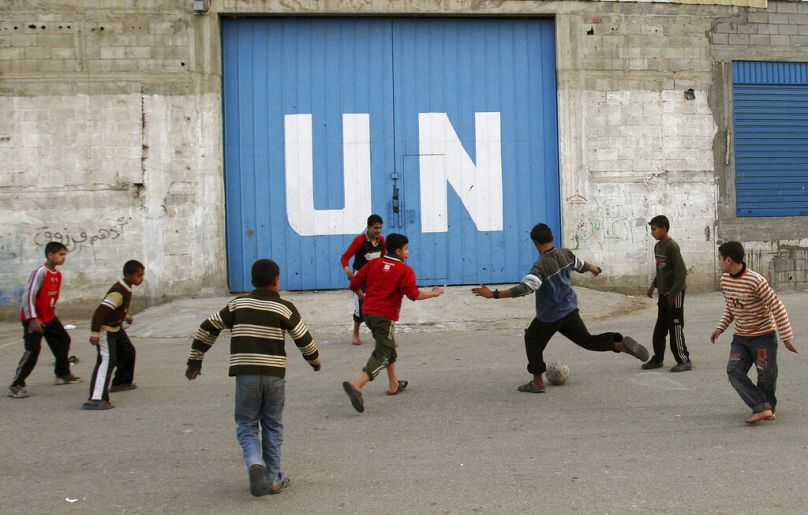 Palestyńskie dzieci grają w piłkę nożną przed bramą centrum dystrybucji żywności ONZ w mieście Gaza, luty 2009 r