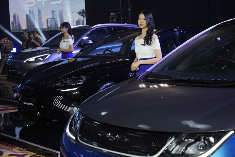 Modele stoją w pobliżu samochodów elektrycznych BYD wystawionych podczas imprezy inauguracyjnej w Dżakarcie, styczeń 2024 r