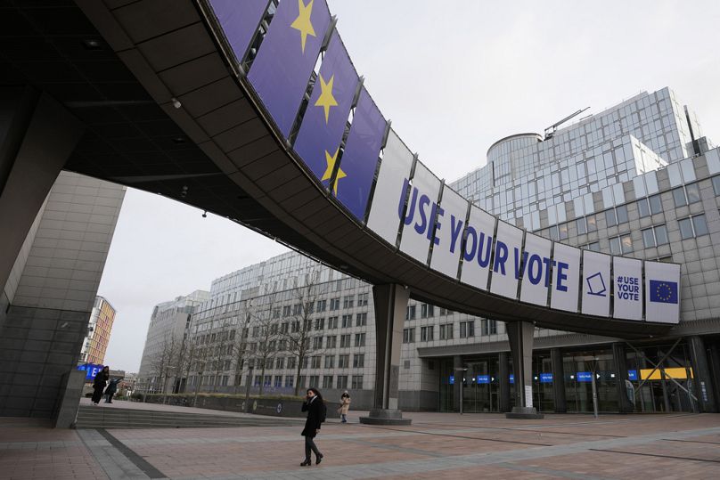 Kobieta przechodzi pod banerem reklamującym wybory europejskie przed Parlamentem Europejskim w Brukseli, styczeń 2024 r