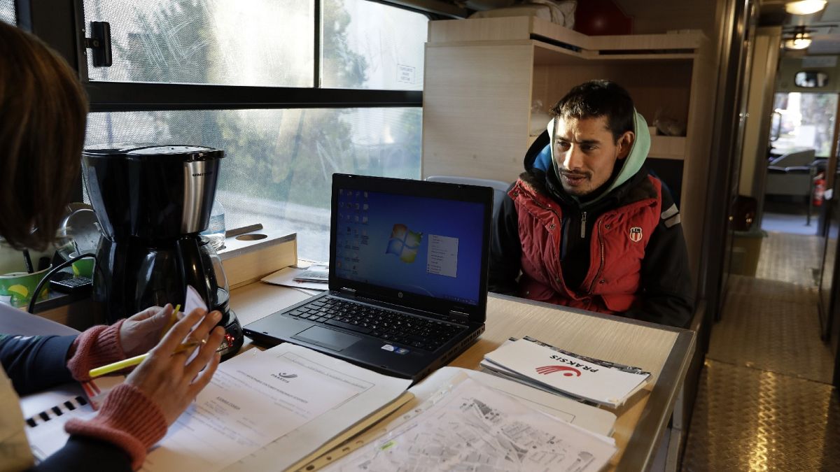 In this photo taken on Monday, Dec. 19, 2016, a homeless person talks with a social worker on the shower bus, run by the Greek Praksis, an NGO, in central Athens.