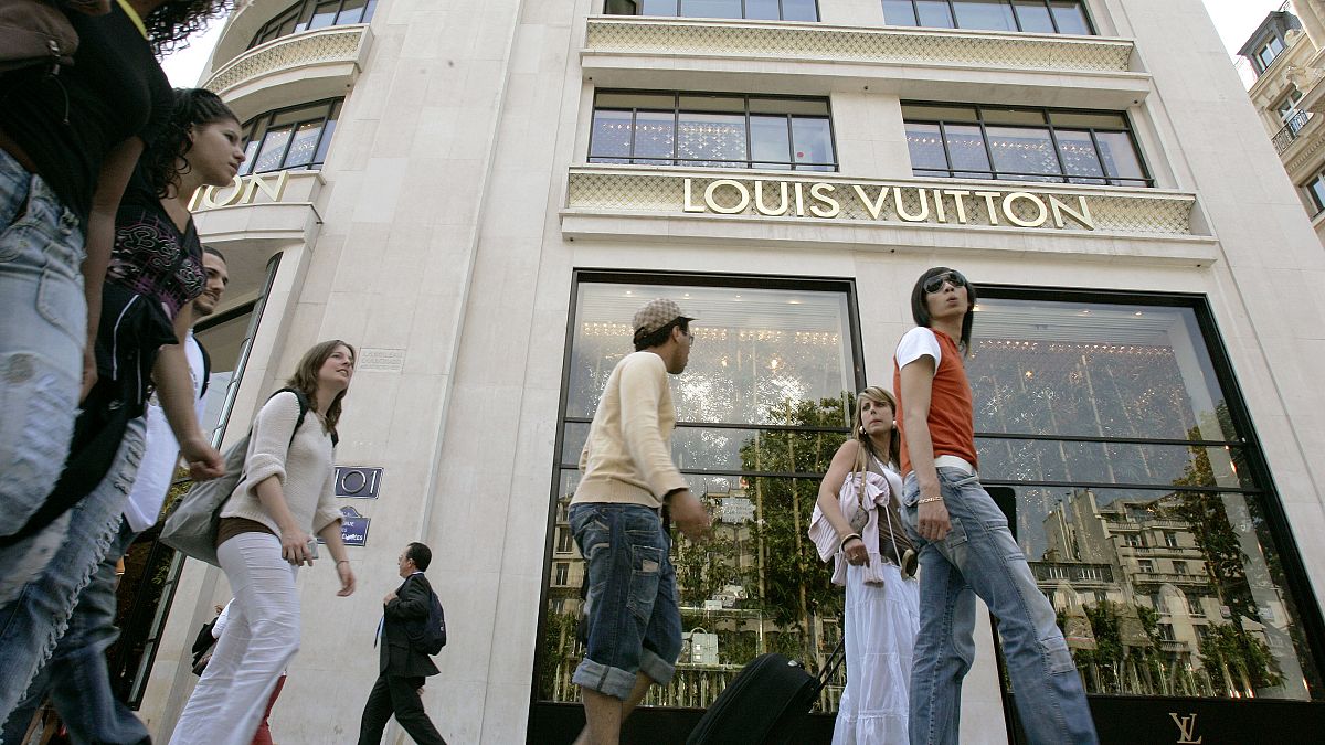 Strollers walk past the Louis Vuitton store on the Champs- Elysee in Paris