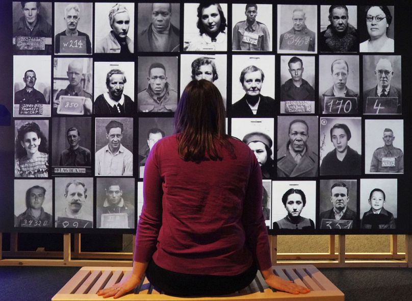 Pracownik obserwuje cyfrową wystawę ze zdjęciami identyfikacyjnymi jeńców wojennych i internowanych cudzoziemców, stanowiącą część wystawy „Wielkie ucieczki” w Archiwum Narodowym.