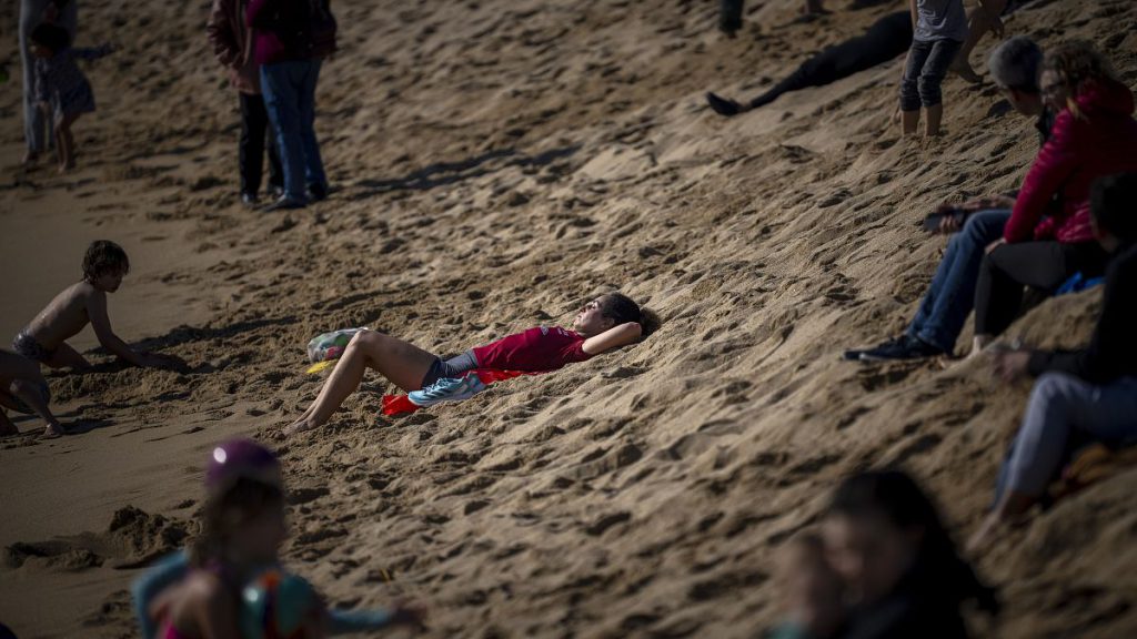 A woman sunbathes at a beach in Barcelona, Spain, Sunday, Feb. 4, 2024. Spain