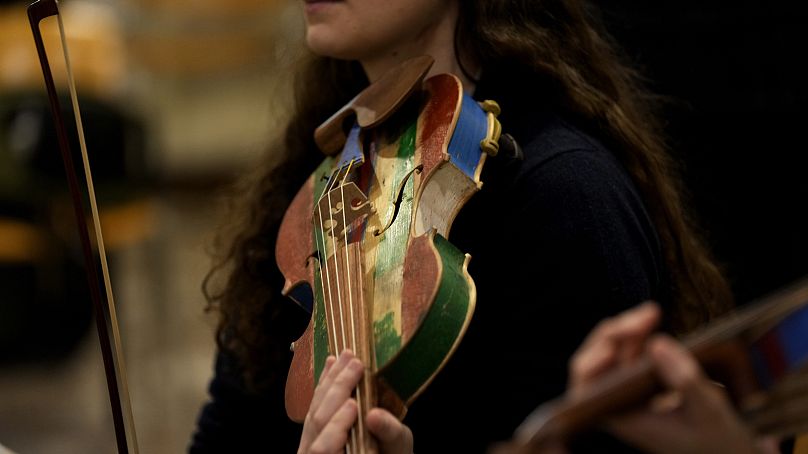 Członkini „Sea Orchestra” ćwiczy ze skrzypcami wykonanymi z drewna z wraków łodzi imigrantów w Mediolanie w północnych Włoszech, sobota, 10 lutego 2024 r.