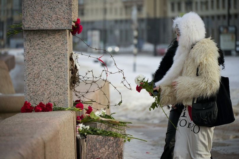 Kobiety składają kwiaty pod Pomnikiem Ofiar Represji Politycznych, aby oddać hołd Aleksiejowi Nawalnemu w Petersburgu, Rosja, wtorek, 20 lutego 2024 r.