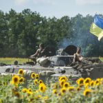 FILE - Ukrainian troops ride on an APC with a Ukrainian flag, in a field with sunflowers in Kryva Luka, eastern Ukraine, Saturday, July 5, 2014.
