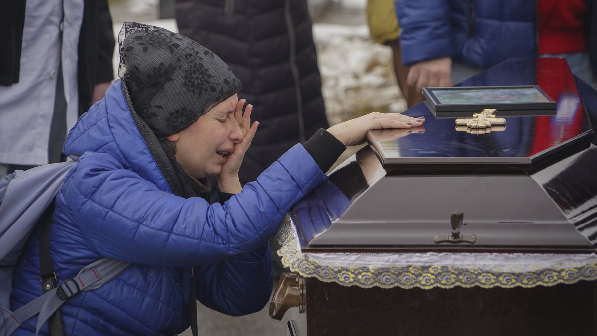 People mourn over the coffins of a family killed in a fire when Russian drone hit their home in residential neighbourhood in Kharkiv, Ukraine, Monday, Feb. 12, 2024.