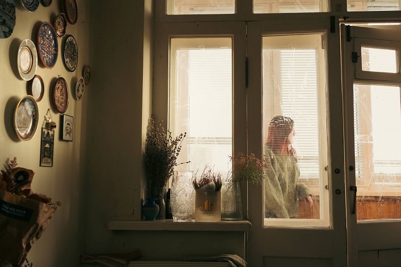 Anna wygląda przez okno w domu swojej przyjaciółki.  Opuściła dom podczas inwazji rosyjskiej 24 lutego 2022 r.