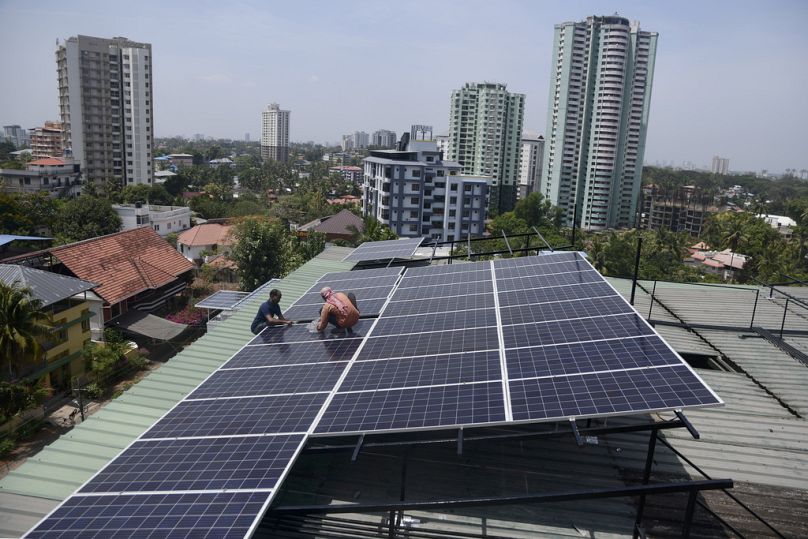 Pracownicy instalują panele słoneczne na dachu mieszkania mieszkalnego w Kochi w południowym stanie Kerala w Indiach.
