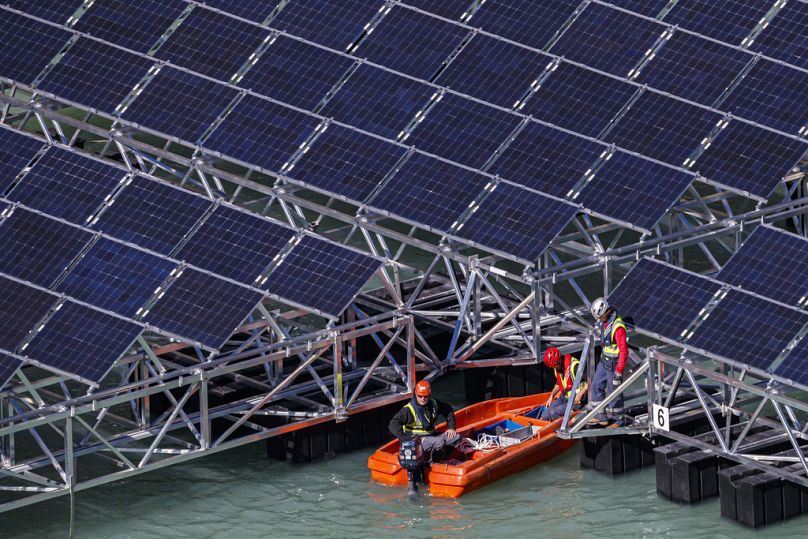 Pracownicy montują pływające barki z panelami słonecznymi na „Lac des Toules”, alpejskim jeziorze zbiornikowym, w Bourg-Saint-Pierre, październik 2018 r.