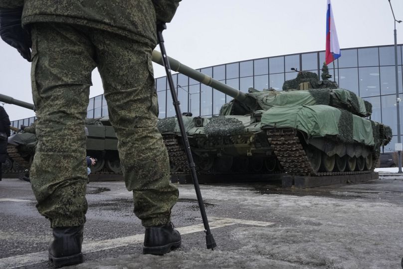 Rosyjski żołnierz stoi obok czołgu T-90 na wystawie broni podczas patriotycznego festiwalu „Rosjanie zmieniają świat” w Sankt Petersburgu, luty 2024 r.