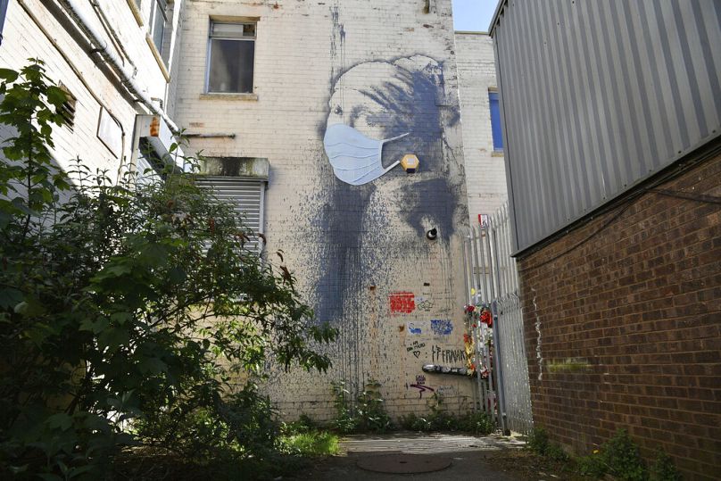 Mural Banksy’ego w Bristolu "Dziewczyna z przebitą błoną bębenkową" ozdobiony maską na twarz w nawiązaniu do trwającej blokady pandemicznej w Wielkiej Brytanii.