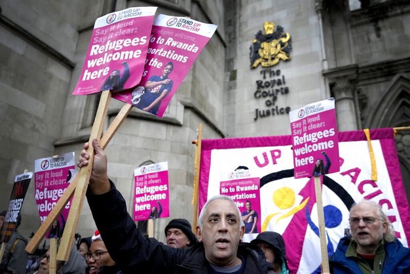 Działacze Stand Up To Racism trzymają banery przed Wysokim Trybunałem w Londynie, grudzień 2022 r