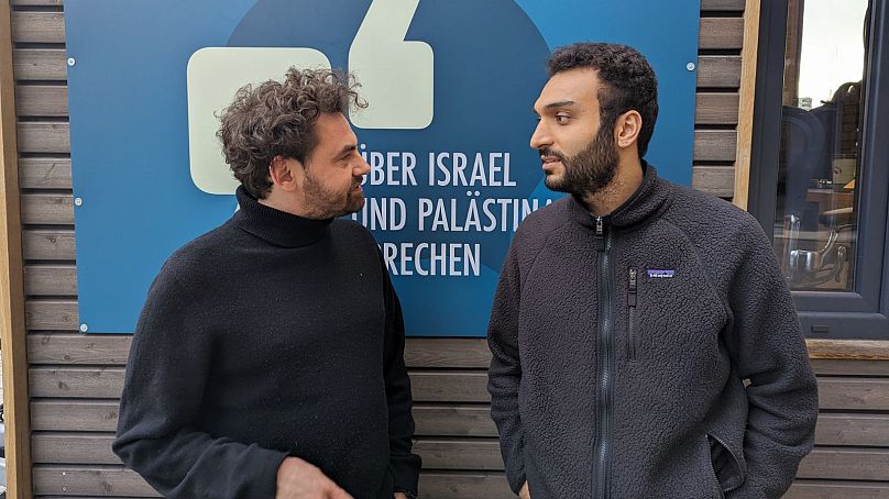 Shai Hoffmann (po lewej) rozmawia z Ahmadem Dakhnousem (po prawej) przed Tiny Space na Potsdamer Platz w Berlinie