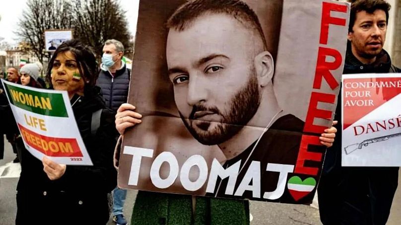 Kobieta trzyma plakat przedstawiający rapera Toomaja Salehiego, który został aresztowany w związku z poparciem protestów Mahsa Amini