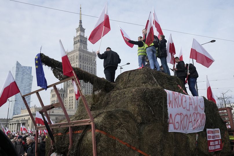 Polscy rolnicy z flagami narodowymi i wściekłymi hasłami wypisanymi na tablicach protestują przeciwko zielonej polityce Unii Europejskiej, Warszawa, Polska