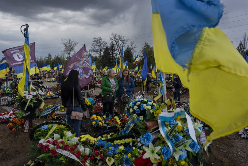 Przyjaciele i krewni odwiedzają grób ukraińskiego żołnierza na cmentarzu Krzywy Rog we wschodniej Ukrainie, niedziela, 23 kwietnia 2023 r.