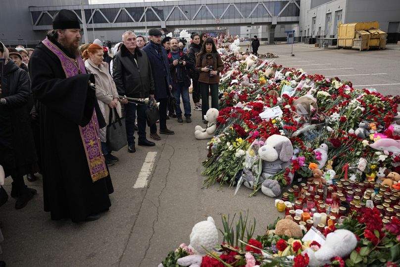 Prawosławny ksiądz odprawia nabożeństwo pod prowizorycznym pomnikiem przed ratuszem Crocus na zachodnich obrzeżach Moskwy, Rosja, wtorek, 26 marca 2024 r.