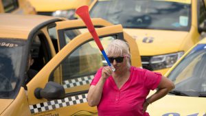 A taxi driver blows into a vuvuzela horn during a protest outside the parliament building in Bucharest, Romania, Tuesday, June 18, 2019.