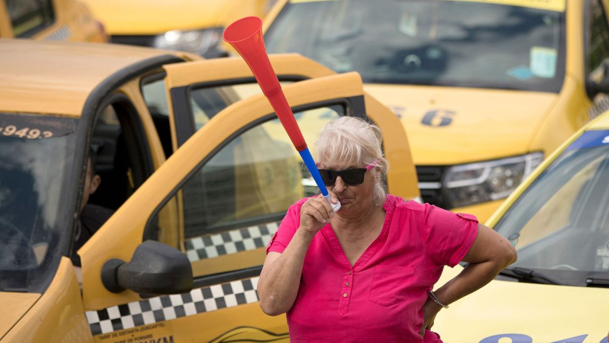 A taxi driver blows into a vuvuzela horn during a protest outside the parliament building in Bucharest, Romania, Tuesday, June 18, 2019.