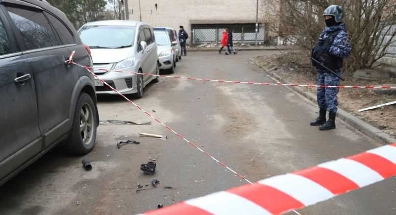 Policjant pilnuje obszaru z wrakiem drona w pobliżu uszkodzonego budynku mieszkalnego po zgłoszonym ataku drona w Petersburgu w Rosji, w sobotę, 2 marca 24.