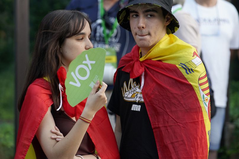 Zwolennicy skrajnie prawicowej partii Vox noszący hiszpańskie flagi na ramionach stoją przed siedzibą partii w Madrycie.